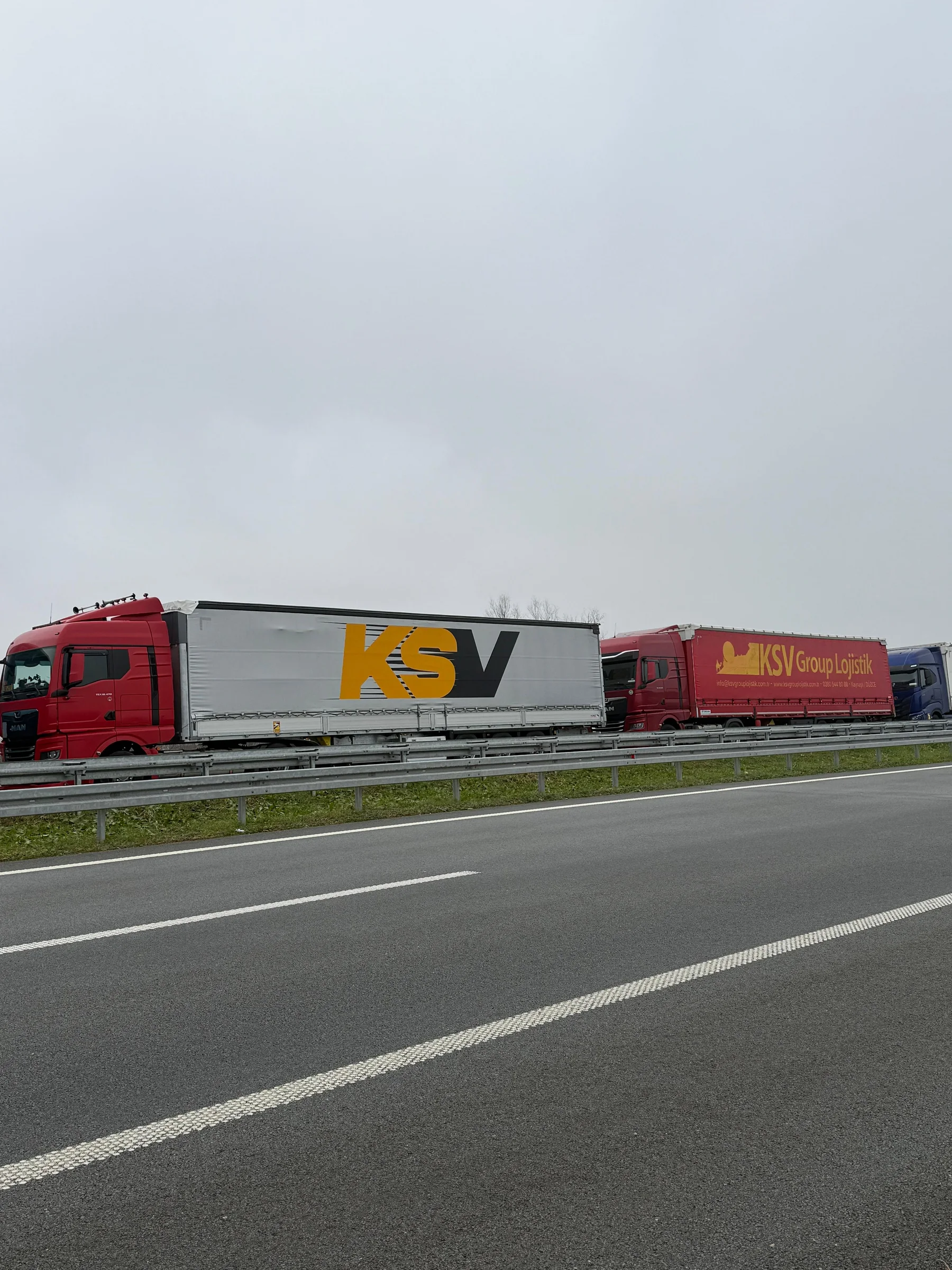 Yol kenarında KSV logolu kırmızı çekiciler ve dorseler